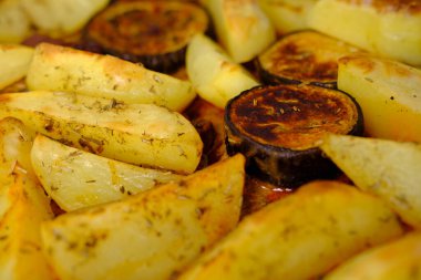 İştah açıcı patatesler, fırında pişmiş patlıcan dilimleri, fırın tepsisinde yatmalar, ev yemeği konsepti, geleneksel yemekler.