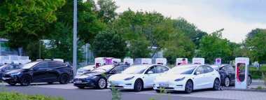 FRANKFURT, Almanya - Ağustos 2021: Amerikan Elon Musk şirketinden Tesla arabaları, bir elektrikli araç üreticisi, TESLA Supercharger, elektrik enerji depolama konseptinde kuyrukta bekliyor