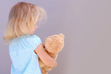 Küçük çocuk, sarışın kız 2 yaşında oyuncakla oynuyor, oyuncak ayıya sarılıyor, mutlu çocukluk, ilk izlenimler, peluş bir arkadaşa masal anlatıyor, onunla ilgileniyor.