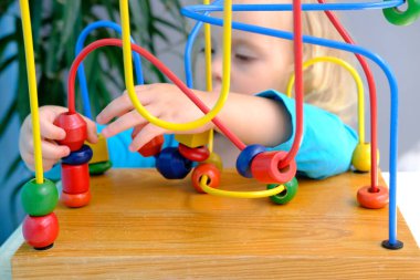 yakın plan zeki küçük çocuk, sarışın bir kız 2 yaşında eğitim oyuncağıyla oynuyor, çocukların labirentlerine bakıyor, konsept çocukluğu, erken eğitim, iyi motor becerilerin gelişimi, düşünme