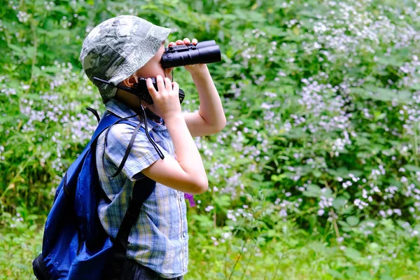 8年の子供 パナマの帽子の少年 手でウォーキートーキーとシャツをプレイした森の中に立って 双眼鏡 オリエンテーリング 野生での生存のハイキングの概念を注意深く見てください — ストック写真