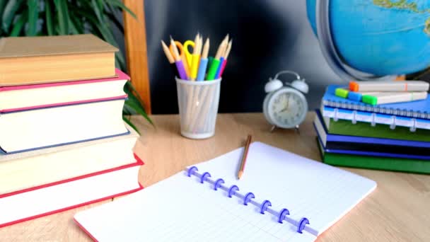 学生家庭办公室桌子上有白色闹钟 彩色笔记本 铅笔在玻璃 粉笔板 地球仪 白色闹钟 教育的概念 回到学校 知识日 — 图库视频影像