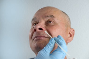Eldivenli erkek doktorun yakın çekimi, analiz için burundan alınan örnek, hızlı nazal test kovid-19, viral hastalığın erken teşhisi, SARS-CoV-2 salgını, koronavirüs...