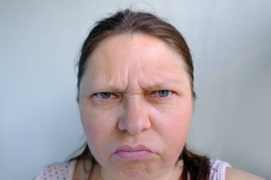 Kızgın, orta yaşlı bir kadın öfkeyle bakıyor, gözlerini kısıyor, yüzünü kapatıyor, stresten duygusal bir patlama, kadın hayatı, öfke.