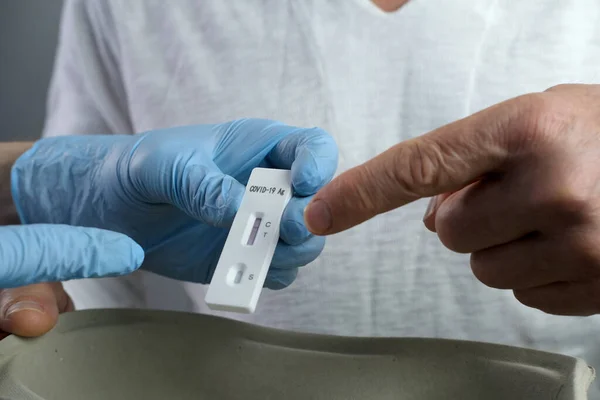 close-up of a male medic\'s hand holding a test cassette, medical disposable sterile test kit for rapid test covid-19, concept of early detection of viral disease, SARS-CoV-2 epidemic, coronavirus
