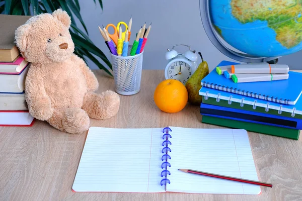 student home office table with white alarm clock, books, teddy bear, colored notebooks, pencils in glass, chalk board, globe, white alarm clock, concept of education, back to school, knowledge day