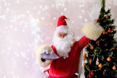 Beyaz sakallı yaşlı Noel Baba çocukları ve yetişkinleri kutluyor, elinde banknotlar tutuyor, onlara Noel konsepti veriyor, tatil indirimleri, alışveriş, hediyeler