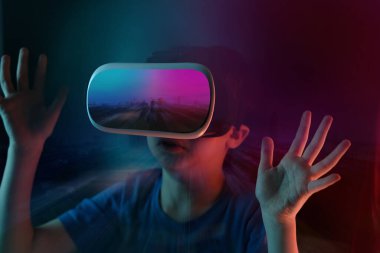 Çocuk, karanlık odada, modern VR gözlüklü bir çocuk sanal gerçeklik deneyimi, başka bir dünyanın konsept çalışması, modern öğretim teknolojileri ile etkileşime geçiyor.