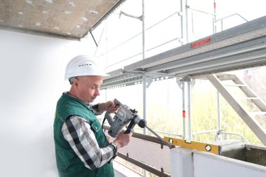 Beyaz kask koruması ve üniformalı el aletleri olan yaşlı inşaat işçisi inşaat ve onarım alanında çalışıyor, inşaat mühendisliği konsepti