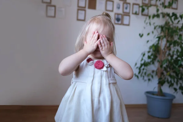 Małe Dziecko Białej Sukience Dziecko Blondynka Złośliwie Zakryła Twarz Dłońmi — Zdjęcie stockowe