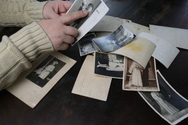 1950 'lerin eski fotoğraflarını gösteren kadın elleri masanın üstünde fotoğraf yığını, soy ağacı konsepti, atalarımızın hafızası, aile ağacı, nostalji, çocukluk anıları.