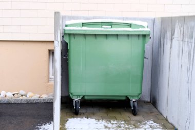 Almanya 'daki apartmanın avlusundaki kamu atık toplama sahasında ayrı ayrı sıralanmak üzere sıralanmış bir dizi plastik yeşil atık konteynırı, temizlik, geri dönüşüm, ev atıklarının atılması