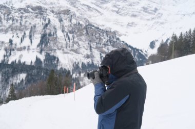 Kameralı yaşlı bir adam, dağ yürüyüşçüsü kış manzarasına hayran, spor konsepti, sağlıklı yaşam tarzı, kış etkinliği, güzel kış doğal manzarası, kışın beyaz ormanda yürüyor.