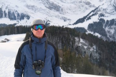 Kameralı yaşlı bir adam, dağ yürüyüşçüsü kış manzarasına hayran, spor konsepti, sağlıklı yaşam tarzı, kış etkinliği, güzel kış doğal manzarası, kışın beyaz ormanda yürüyor.