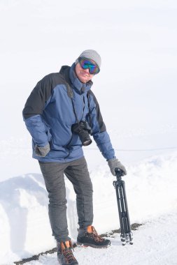 Kameralı yaşlı bir adam, dağ yürüyüşçüsü kış manzarasına hayran, spor konsepti, sağlıklı yaşam tarzı, kış etkinliği, güzel kış doğal manzarası, kışın beyaz ormanda yürüyor.