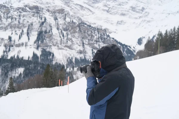 Kameralı yaşlı bir adam, dağ yürüyüşçüsü kış manzarasına hayran, spor konsepti, sağlıklı yaşam tarzı, kış etkinliği, güzel kış doğal manzarası, kışın beyaz ormanda yürüyor.