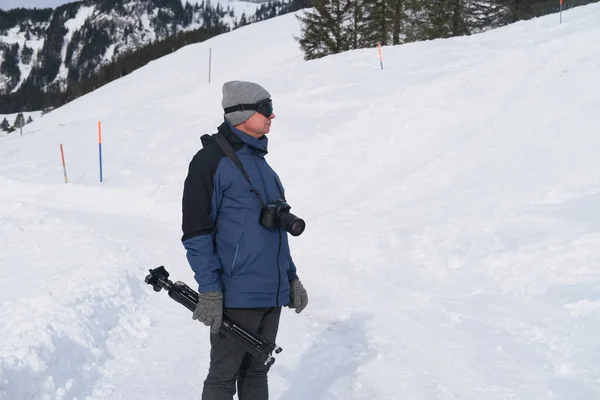 elderly man with camera, mountain hiker admiring mountain winter landscape, Sports Concept, Healthy Lifestyle, Winter Activity, beautiful winter natural landscape, walks in winter white forest