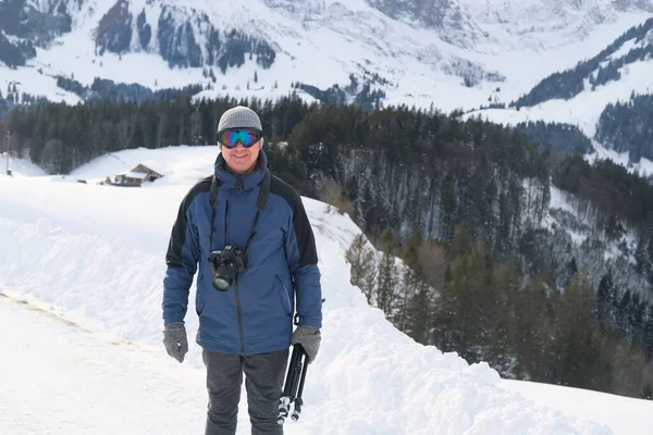 Kameralı yaşlı bir adam, dağ yürüyüşçüsü kış manzarasına hayran, spor konsepti, sağlıklı yaşam tarzı, kış etkinliği, güzel kış doğal manzarası, kışın beyaz ormanda yürüyor.