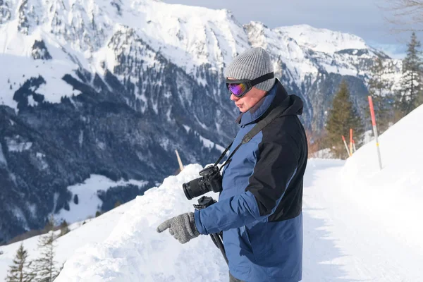 Kameralı yaşlı bir adam, dağ yürüyüşçüsü kış manzarasına hayran, spor konsepti, sağlıklı yaşam tarzı, kış etkinliği, güzel kış doğal manzarası, kışın beyaz ormanda yürüyor.