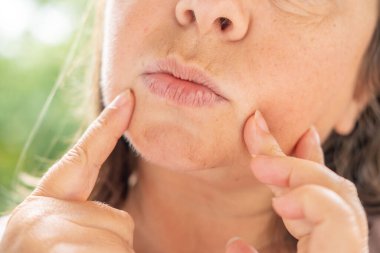 50 yaşında orta yaşlı bir kadın, insan kulağı çınlıyor, dinliyor, akustik işitme sistemi, işitme testi, koklear implant, yardımcı dinleme cihazı, sağlıklı yaşlanma, kaliteli olgun yaşam, sağlık kontrolü. 