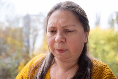 50 yaşında orta yaşlı bir kadın, insan kulağı çınlıyor, dinliyor, akustik işitme sistemi, işitme testi, koklear implant, yardımcı dinleme cihazı, sağlıklı yaşlanma, kaliteli olgun yaşam, sağlık kontrolü. 