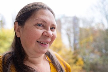 50 yaşında orta yaşlı bir kadın, insan kulağı çınlıyor, dinliyor, akustik işitme sistemi, işitme testi, koklear implant, yardımcı dinleme cihazı, sağlıklı yaşlanma, kaliteli olgun yaşam, sağlık kontrolü. 