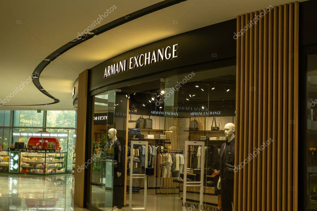 Armani Exchange fashion store front with illuminated signage wooden slats and modern interior design, Mannequins display fashion lifestyle products in Tirana, Albania - September 10, 2025