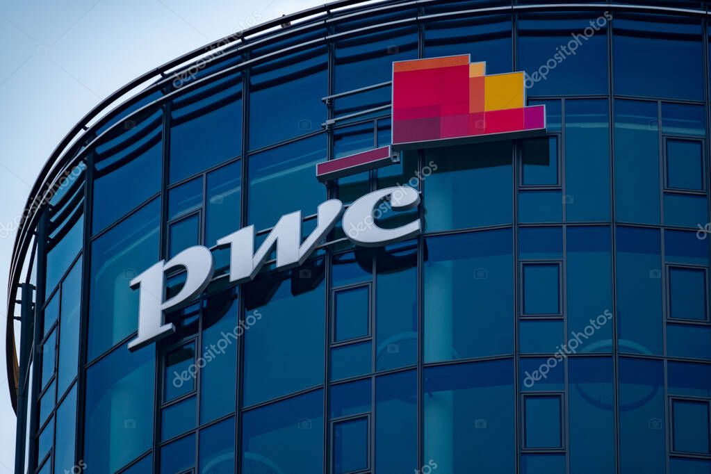 PwC logo on glass facade, high-rise glass office building against blue sky, finance and consulting, global economy, professional financial services in Germany, Frankfurt - February 9, 2025