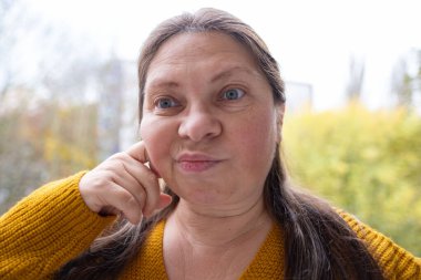 Kuşkucu olgun kadın açık havada, kadın yüzü hayal kırıklığını, şüpheciliği ve duygusal acıyı gösteriyor. Yakın plan, hayal kırıklığını ve şüpheyi gergin bir pozla ifade eden kadın modeli.