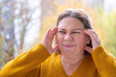 Yetişkin bir kadın menopoz, yüksek tansiyon, baş tutma ve yüksek tansiyon nedeniyle sıcak basmalar yaşıyor. Sağlık sorunları, yüz ifadesi