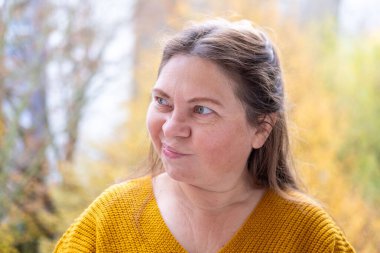 Kuşkucu olgun kadın açık havada, kadın yüzü hayal kırıklığını, şüpheciliği ve duygusal acıyı gösteriyor. Yakın plan, hayal kırıklığını ve şüpheyi gergin bir pozla ifade eden kadın modeli.