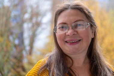 Kendine güvenen, orta yaşlı, 55 yaşında, uzun saçlı, doğal güzelliği kucaklayan, kendine güvenen, kendine güvenen, iç huzuru ve güveni olan, zamansız kadınsı bir kadın.