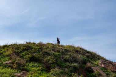 Mutlu genç çocuk volkanik uçurum kenarında duruyor, Madeira adasında yürüyüş yapıyor, sonsuz mavi Atlantik okyanusuna bakıyor, okyanus kıyısında dinlendirici yürüyüşün tadını çıkarıyor.