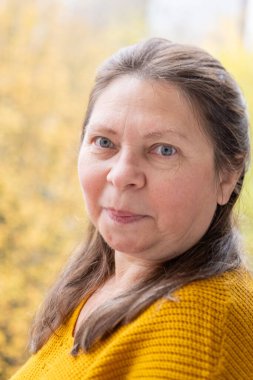 Gülümseyen orta yaşlı kadın uzun saçlı, kendini beğenmiş, kendine güvenen, doğal yaşlanma, pozitif ruh hali, yakın görüş, açık hava ışığı, sağlıklı yaşam tarzı, yakın yüz görünümü, sağIık teması