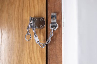 Kapı zincirinden bakmak, güvenlik kontrolü, şüpheli bir an, kapalı mekan, güvenlik endişesi, yabancı korku, kişisel alan, ek kapı koruması.