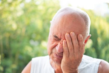 60-65 yaş arası mutsuz, kederli yaşlı bir adam, ellerle gözlerini kapatıyor, gözyaşları akıyor, yaşlanmış keder, duygusal sıkıntı