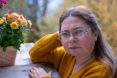 Kuşkucu olgun kadın açık havada, kadın yüzü hayal kırıklığını, şüpheciliği ve duygusal acıyı gösteriyor. Yakın plan, hayal kırıklığını ve şüpheyi gergin bir pozla ifade eden kadın modeli.