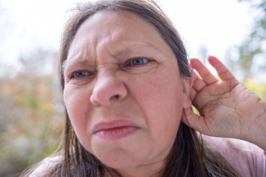 Yetişkin, beyaz bir kadın, 50 yıl boyunca el ele tutuşmuş, yüzü yaralı kadın yüzünü kapatmış, kulaklarında çınlama, kulak çınlaması, orta kulak iltihabı, akustik travma...