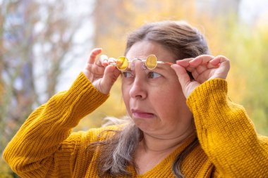 50 yaşında gözlük takan olgun bir kadın, kötü görüş, miyop sorunu, optik muayene, diopter hassasiyeti, gözlüklü bir kadın, doğru lens diopterleri, görüş sağlığı, duygusal portre, yaşlanma