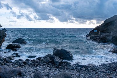 Madeira Adası 'nda Atlantik Okyanusu' nun üzerinde dramatik volkanik kayalıklar yükselir, doğal manzara, jeolojik güzellik, deniz manzarası, lav kayaları ve derin mavi okyanus, vahşi doğa, uzak ada, Atlantik hazinesi.