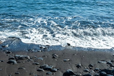 Madeira 'daki siyah volkanik kumsal ve mavi su okyanusu, Portekiz kıyıları, Atlantik dalgaları güneşte parlıyor, sıcak Körfez akıntısı su akıntıları, seyahat rüyası, huzurlu enerji, deniz yaşamı