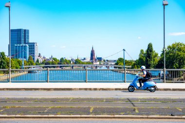 Köprüde mavi scooter, modern Frankfurt am Main City Skyline ile gökdelenler, sokak manzarası, mavi gökyüzü, Avrupa şehri Frankfurt am Main, Almanya - 11 Ağustos 2025
