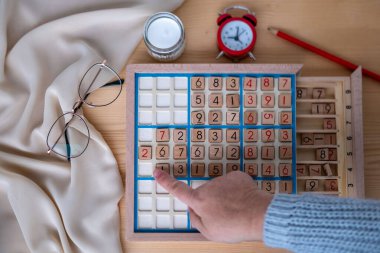 Kadınların ellerini dikkatlice Sudoku bulmacası içine yerleştirirken, meydan okuyan bulmacaları çözmeye kendini kaptırmış yaşlı insanlar, beyin sağlığı, zihinsel aktivite klasik oyunu