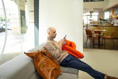 Programcı, kahverengi kablo örgü süveter giyen genç adam bilgisayarda çalışıyor, fincan çay sunan kadın, modern ev ofis ortamı üretkenliği ve sakin ve destekleyici ilişkiyi destekliyor. 