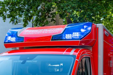 Alman itfaiye minibüsünde mavi ışıklar, şehir caddesinde park etmiş acil ambulans, itfaiye, kırmızı kurtarma aracı, tıbbi müdahale, Frankfurt, Almanya - 26 Temmuz 2025