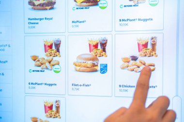 Dokunmatik ekran menüsünden yemek siparişi veren genç kadın, McDonalds 'ta, dijital büfe fast food restoranında, el sıkışma ekranında, hızlı servis, menü tercihleri, Frankfurt - 21 Nisan 2025