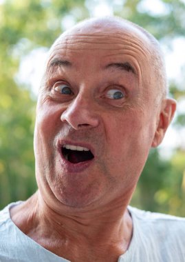 Bereli ve yelekli yaşlı bir adam markette taze domates inceliyor, erkek alışverişçi süpermarkette sebze seçiyor, sebze reyonundan sebze seçerken odaklanmış ifade kullanıyor.