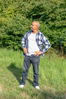 Bereli ve yelekli yaşlı bir adam markette taze domates inceliyor, erkek alışverişçi süpermarkette sebze seçiyor, sebze reyonundan sebze seçerken odaklanmış ifade kullanıyor.