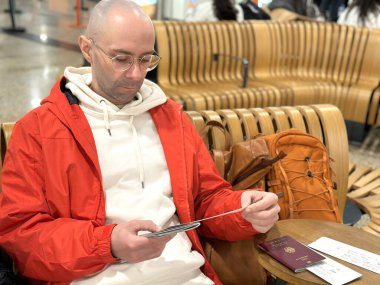 Erkek yürüyüşçü, kırmızı yağmurluklu genç adam kayalık dağ yolunda duruyor, açık hava macerası ve seyahat teknolojisi, aktif yaşam tarzı, doğa keşfi, huzur ve sükunet bulma, dağ yürüyüşü