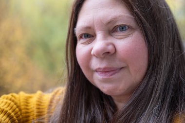 Rahatlamış tombul bir kadın, mutluluğu nazikçe kucaklıyor, doğada duruyor, sıcak kalpli bir kadın, sevgisini ve takdirini ifade ediyor, olgun bir kadın yüzü, kendine bakım, rahatlama ve ahenk kavramını kavrıyor.